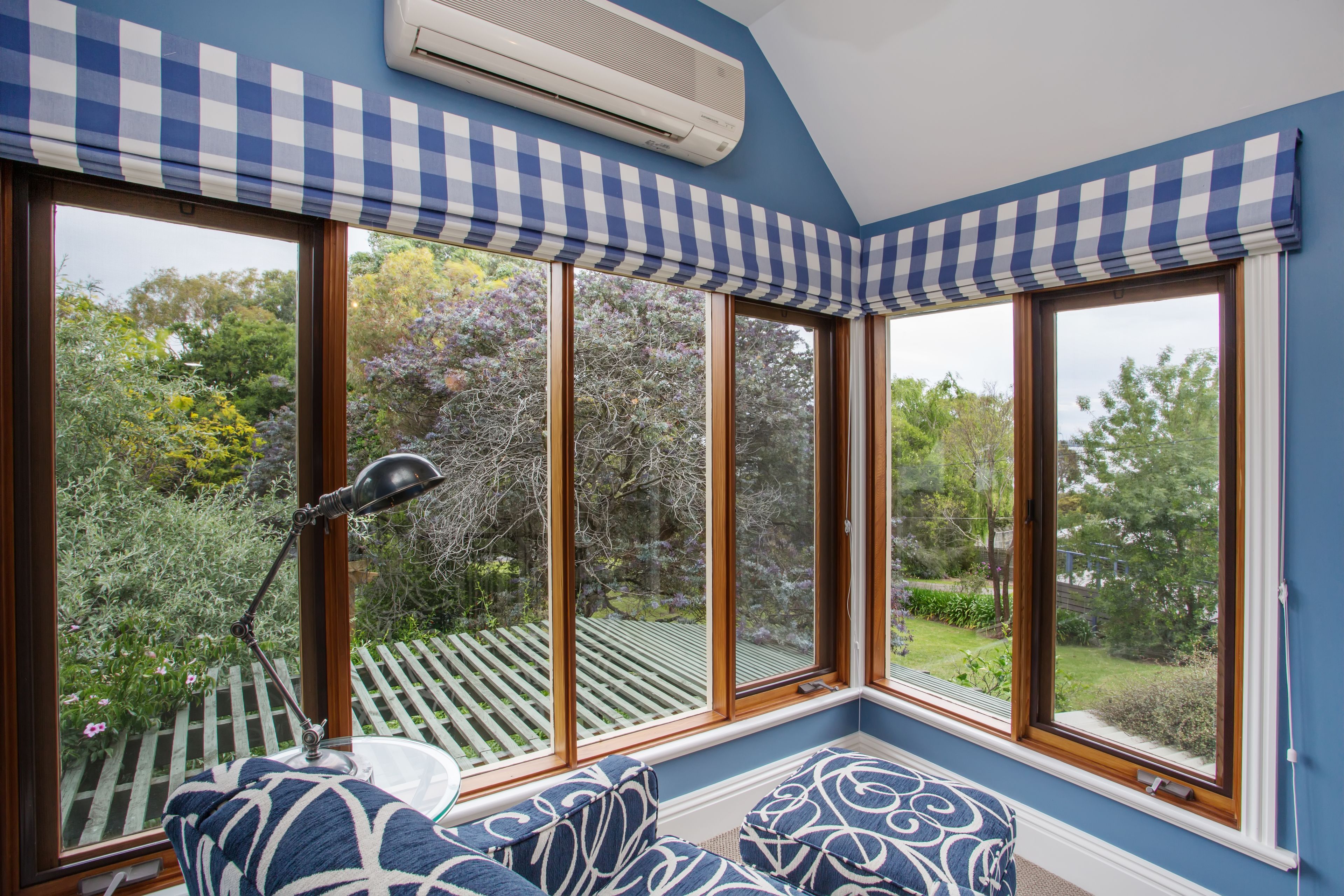 A room with large windows, a desk, and a chair.