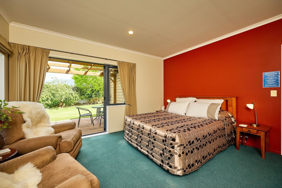 Una habitación de hotel con una cama, una silla, una mesita y vistas al exterior.