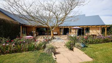 A house with a covered patio, a garden with flowers, and a brick exterior.