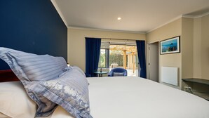A hotel room with a large bed, a small table, a chair, and a view of the outdoors. - Awatea Country B&B (Hapuku)