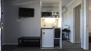 A compact kitchenette with a microwave, refrigerator, and a small table. - Aastro Dish Motor Inn (Parkes)