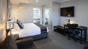 A modern hotel room with a bed, desk, chair, and a flat-screen TV. - Aastro Dish Motor Inn (Parkes)