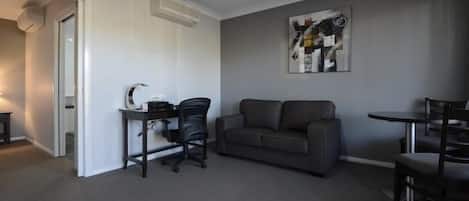 Una sala de estar moderna con un sofá gris, una mesita y un escritorio con una silla.