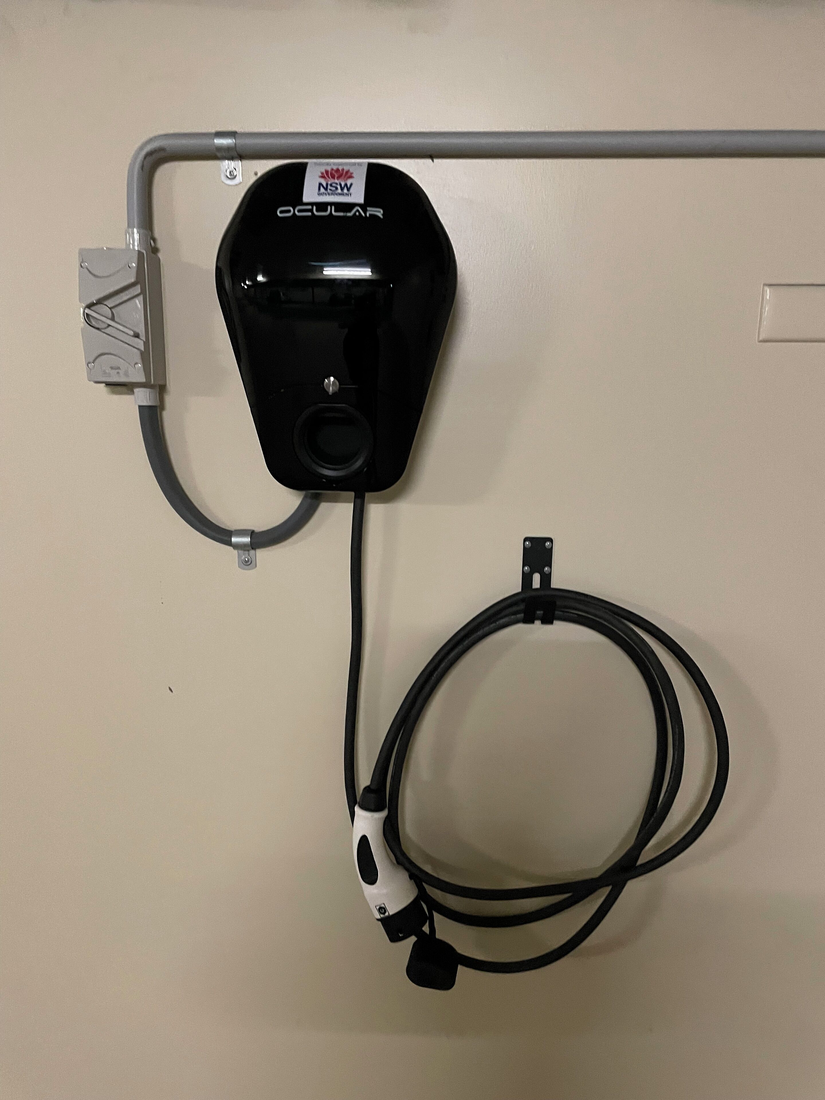 Un dispositivo ocular negro montado en una pared, con una tubería gris y un cable blanco conectados.