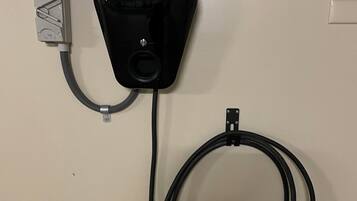 Un dispositivo ocular negro montado en una pared, con una tubería gris y un cable blanco conectados.