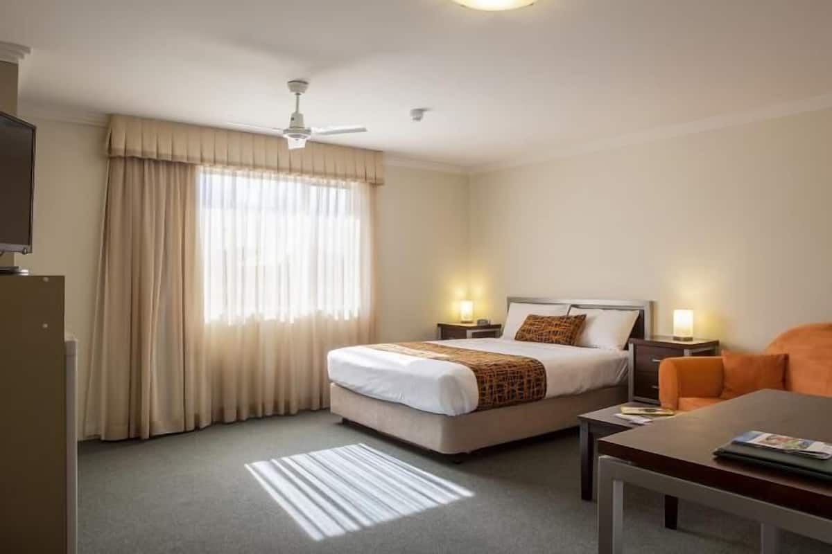 Una habitación de hotel con cama, mesitas de noche, un escritorio y una silla.