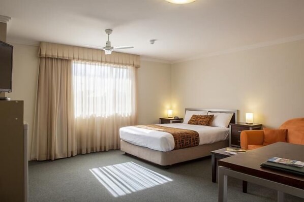 A hotel room with a bed, bedside tables, a desk, and a chair.