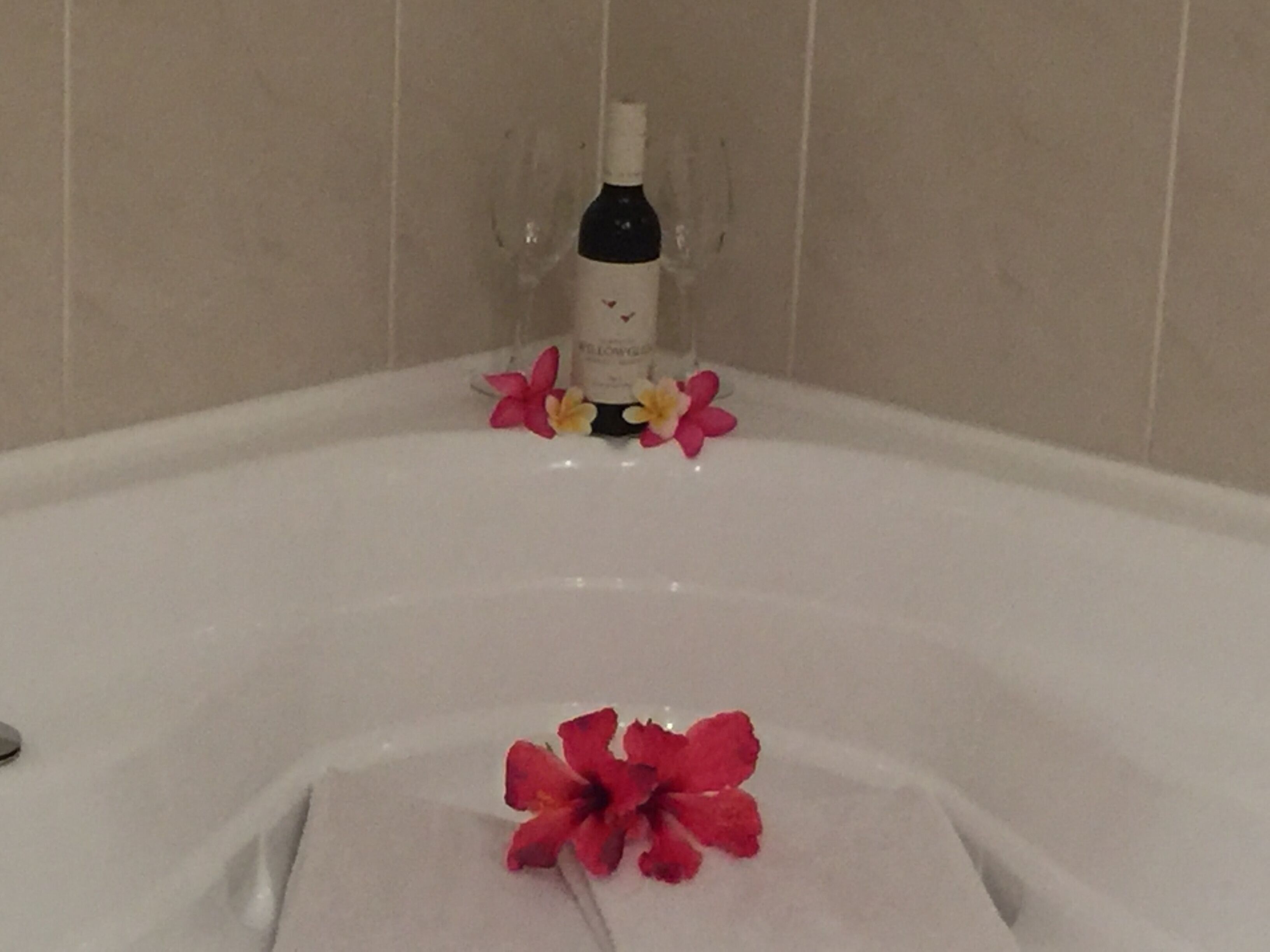 A bathtub with a bottle of shampoo and a few flowers.