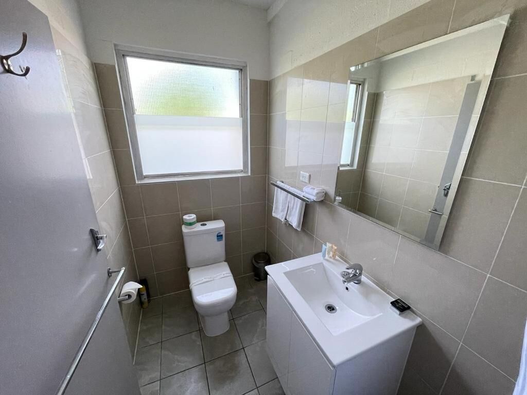 A bathroom with a toilet, sink, and window.