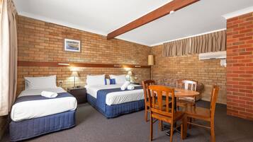 A hotel room with two beds, a small table, and a chair.