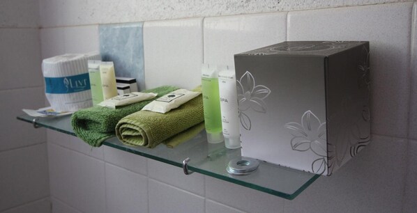A bathroom shelf with toiletries, a green towel, and a box with floral design. - Gulgong Motel (Gulgong)