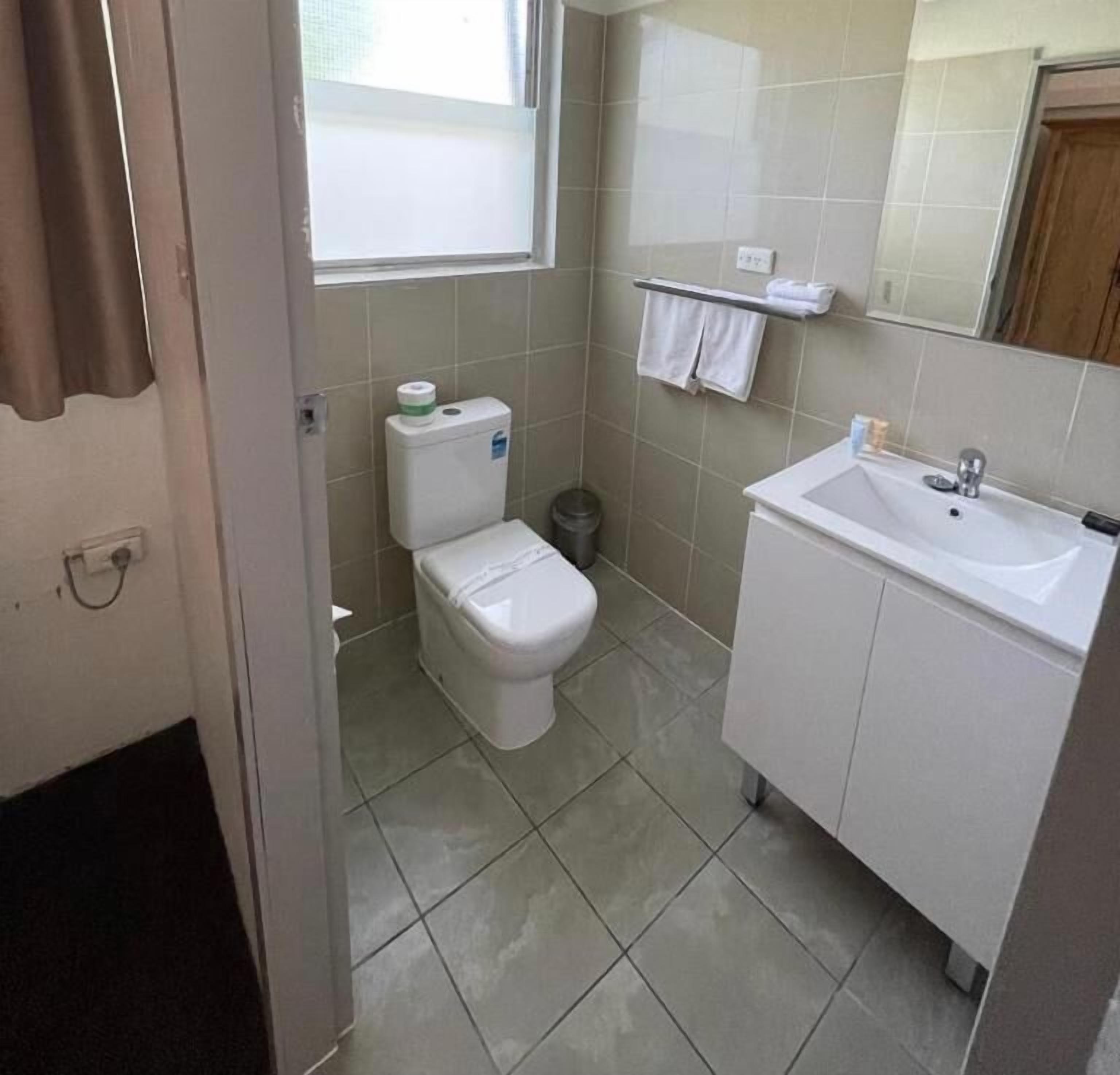 A small, clean bathroom with a toilet, sink, and a window.