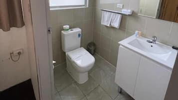 A small, clean bathroom with a toilet, sink, and a window.
