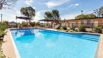 Relax by the pool surrounded by lush greenery and trees.