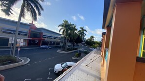 A street view with a building featuring a red entrance and a parking lot. - McGuire's CBD Hotel (Mackay)