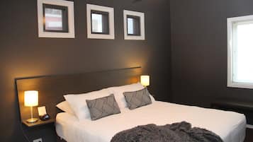 A bedroom with a bed, bedside lamps, a nightstand, and three framed pictures on the wall.