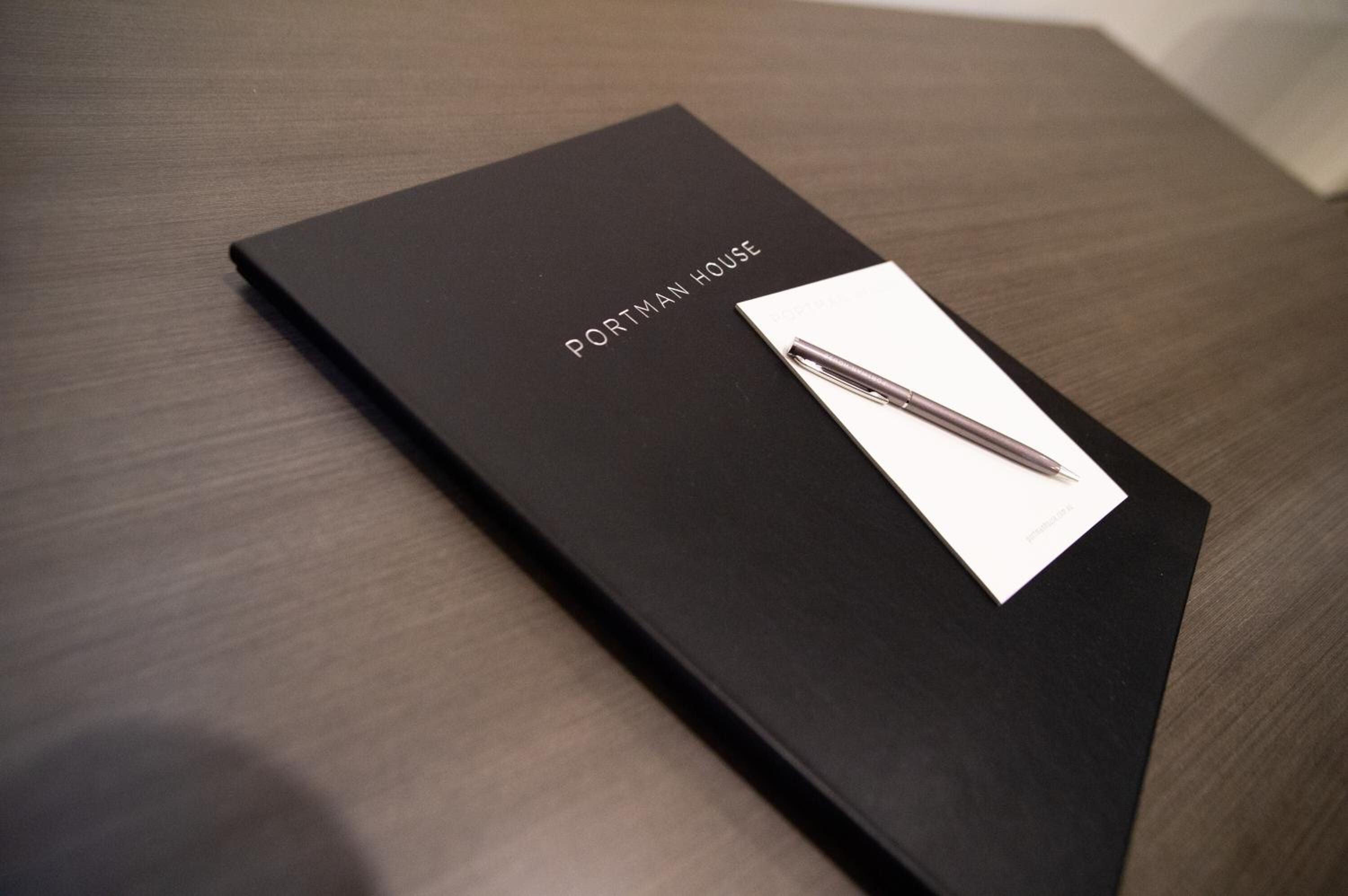 En svart pärm med texten ”PORTMAN HOUSE” på, placerad på en träyta.