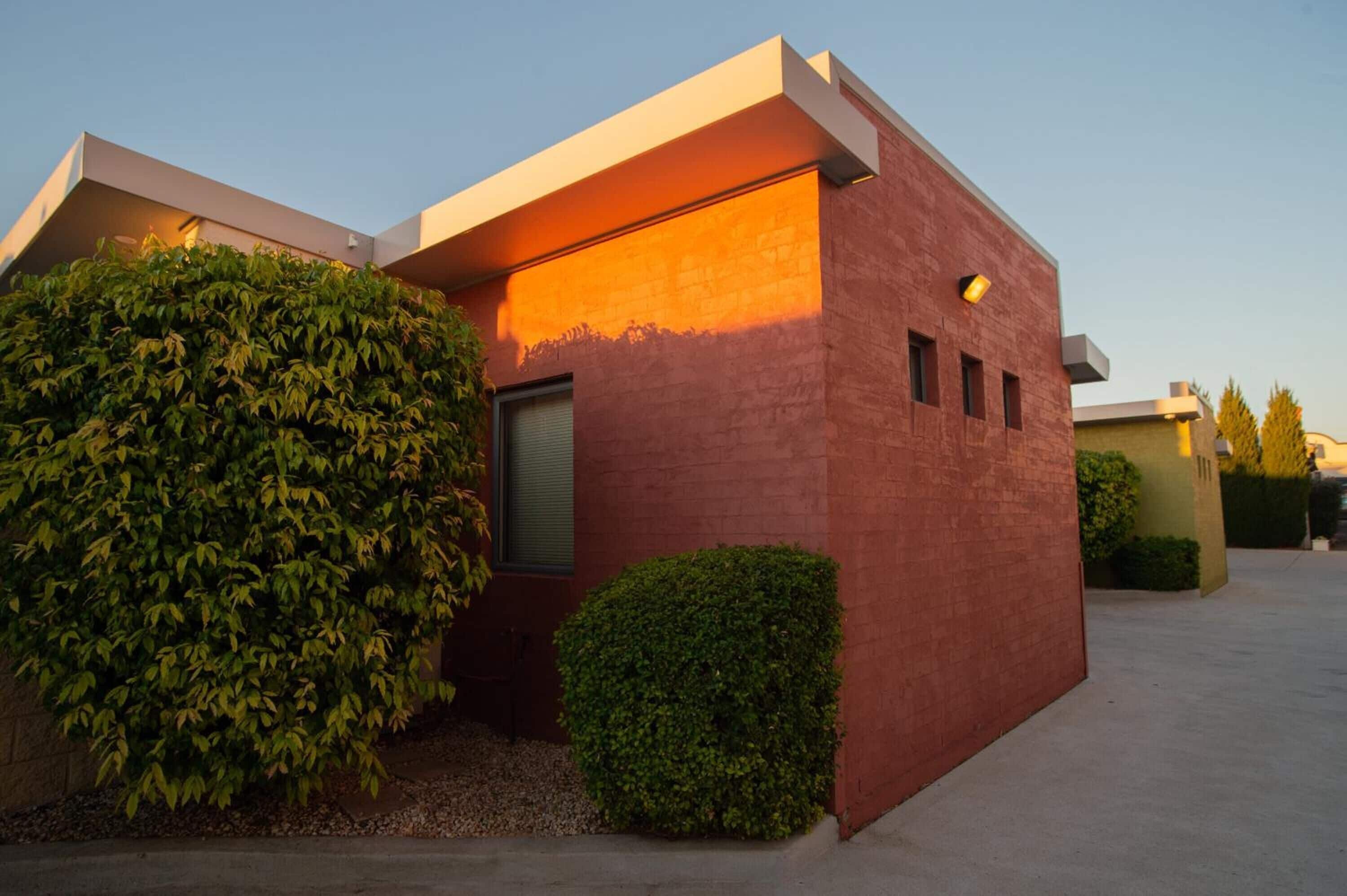 A modern building with a flat roof, a large window, and a small door.