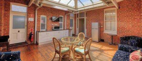 A spacious kitchen with a glass ceiling, a dining area with wicker chairs, and a refrigerator.