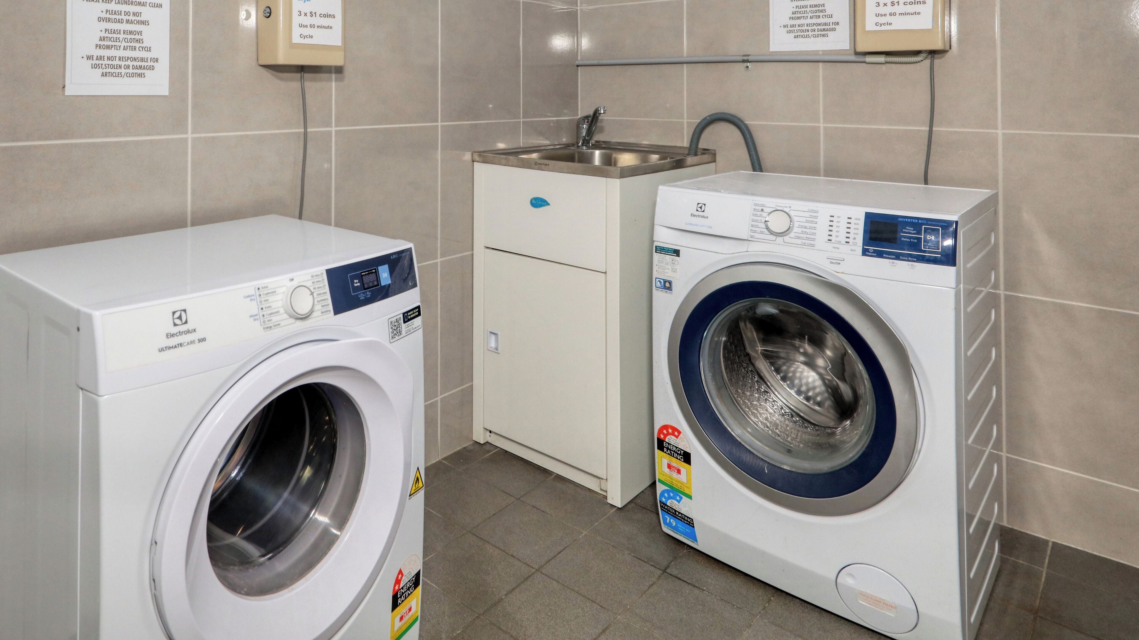A laundry area with two washing machines, a sink, and a cabinet.