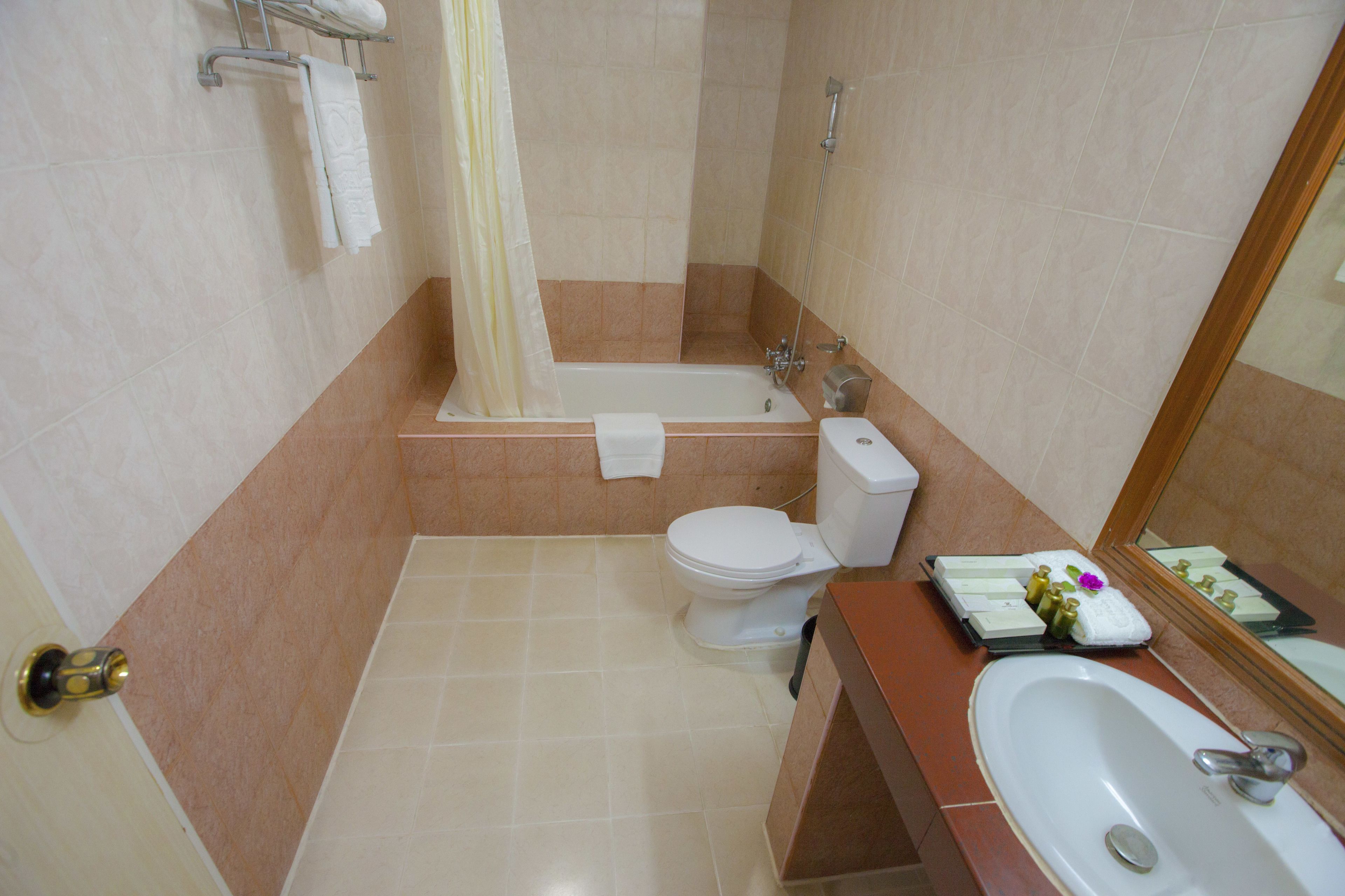 Un baño con bañera, inodoro, lavamanos y cortina de ducha.