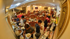 A buffet setup with multiple food stations and guests serving themselves. - Grand Palace Hotel (Yangon)