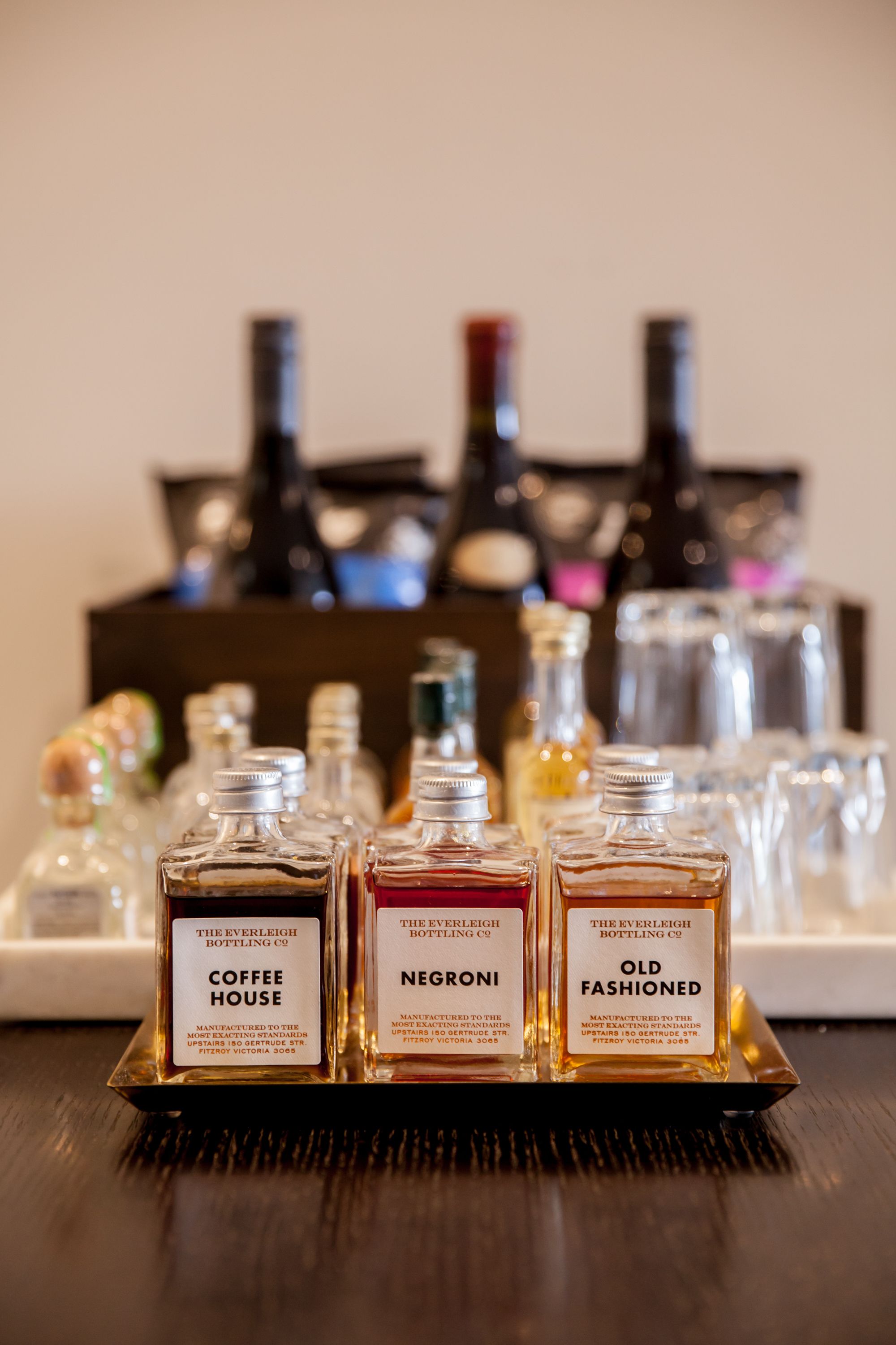 A tray with three bottles labeled 'Coffee House,' 'Negroni,' and 'Old Fashioned.'