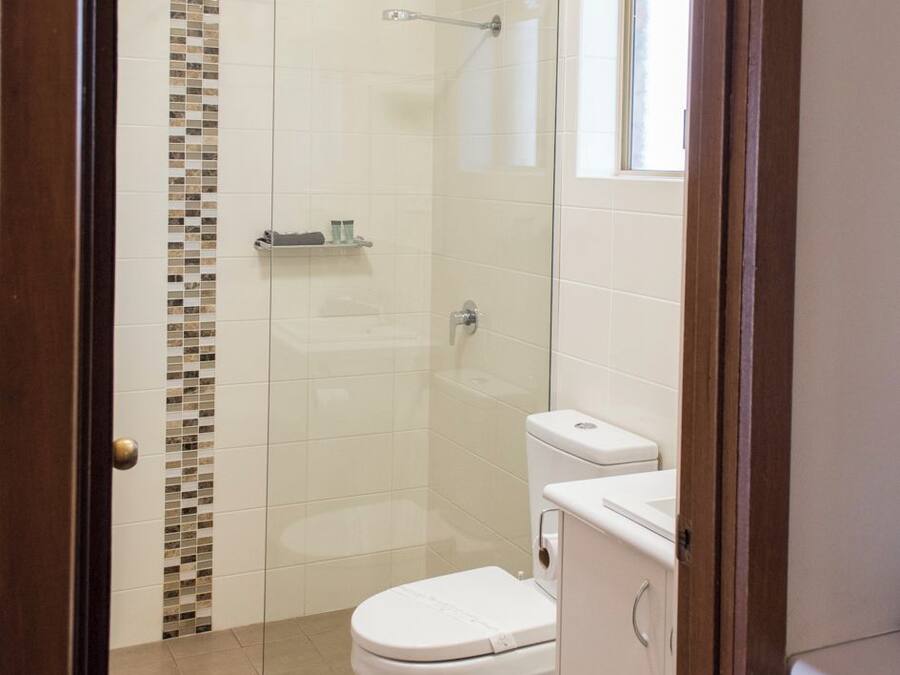 Un baño con ducha de vidrio, inodoro y lavamanos.