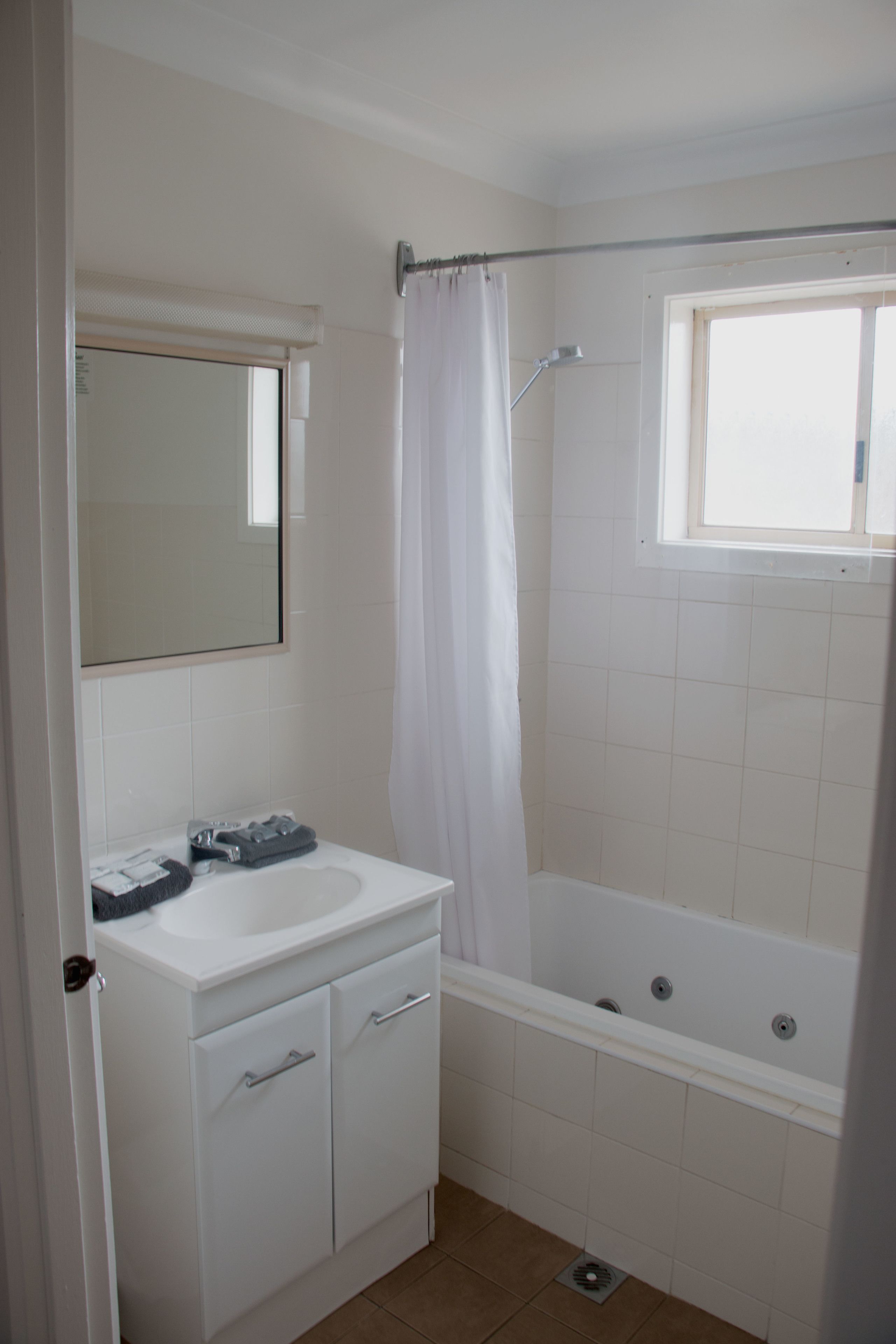 Un baño con lavamanos blanco, espejo y bañera.