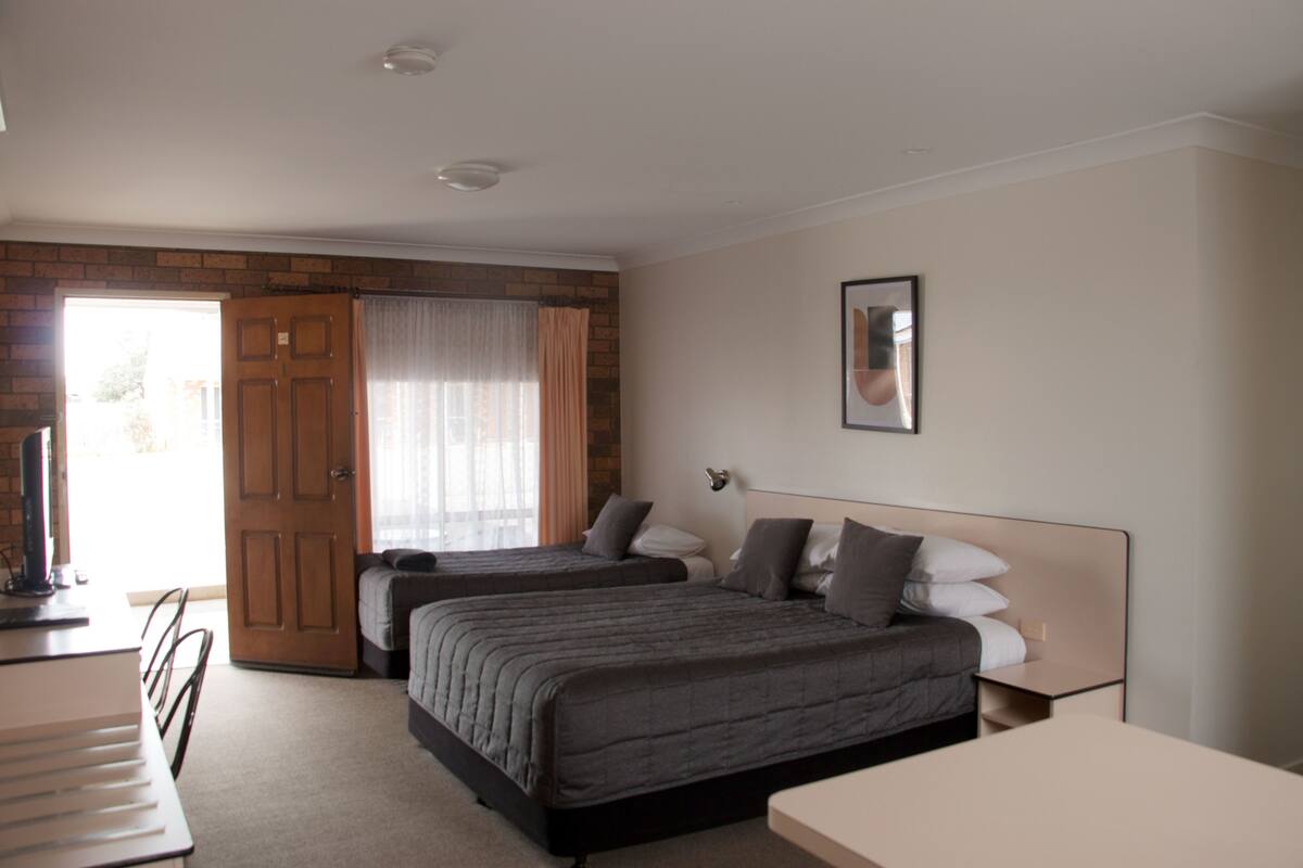 A hotel room with two beds, a desk, and a chair.