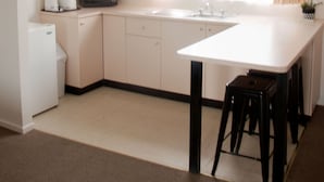 A compact kitchen with a white countertop, a sink, a microwave, and a small refrigerator. - Highway Inn Motel (Hay)