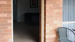 An open doorway leading to a room with a dark-colored sofa and a framed picture on the wall. - Highway Inn Motel (Hay)