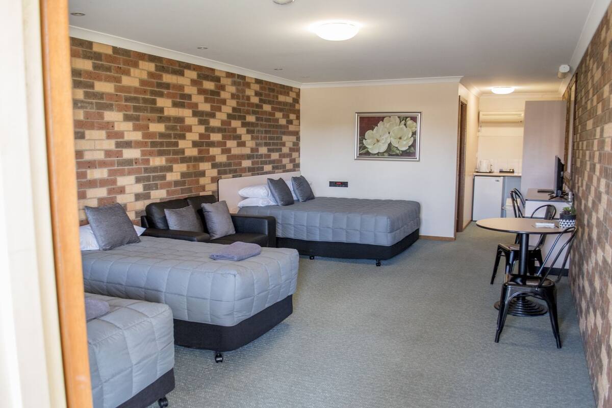 A compact room with two beds, a small kitchenette, and a dining area.