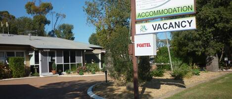 A signboard for a tourist park named "Roma Aussie" indicating accommodation and vacancy availability.