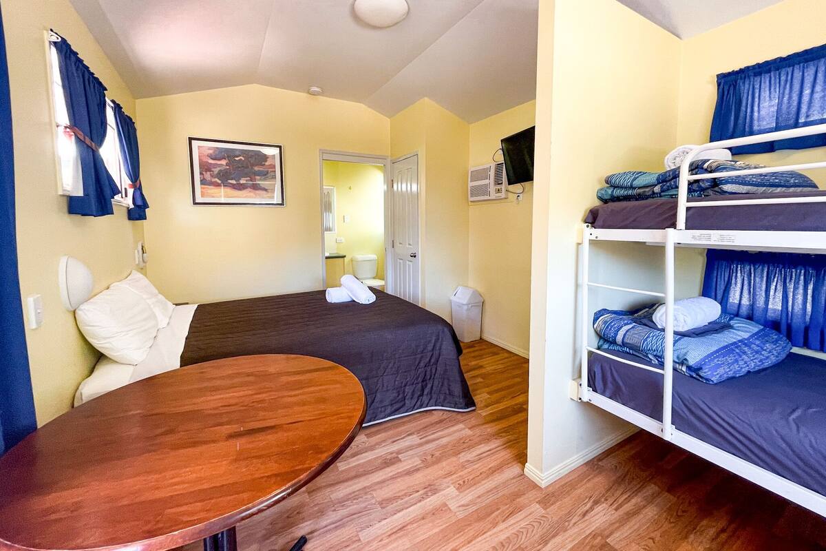 Una habitación de hotel compacta con una cama individual, una mesita pequeña y una cama litera.