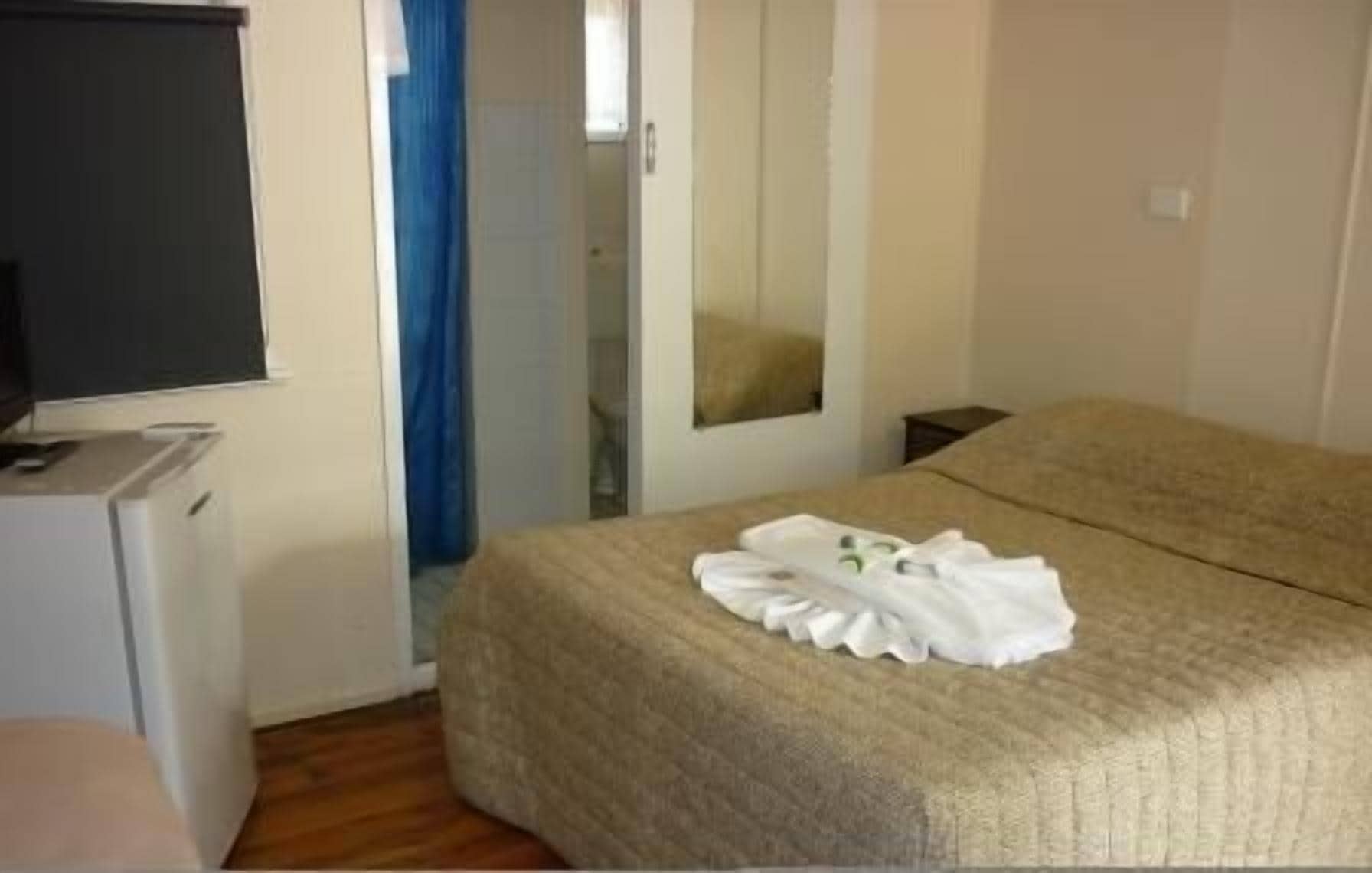 A hotel room with a bed, a TV, a desk, and a bathroom visible through a door.