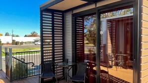 Un espace extérieur abrité, aménagé avec des tables et des chaises, une terrasse en bois et offrant une vue sur le paysage environnant.