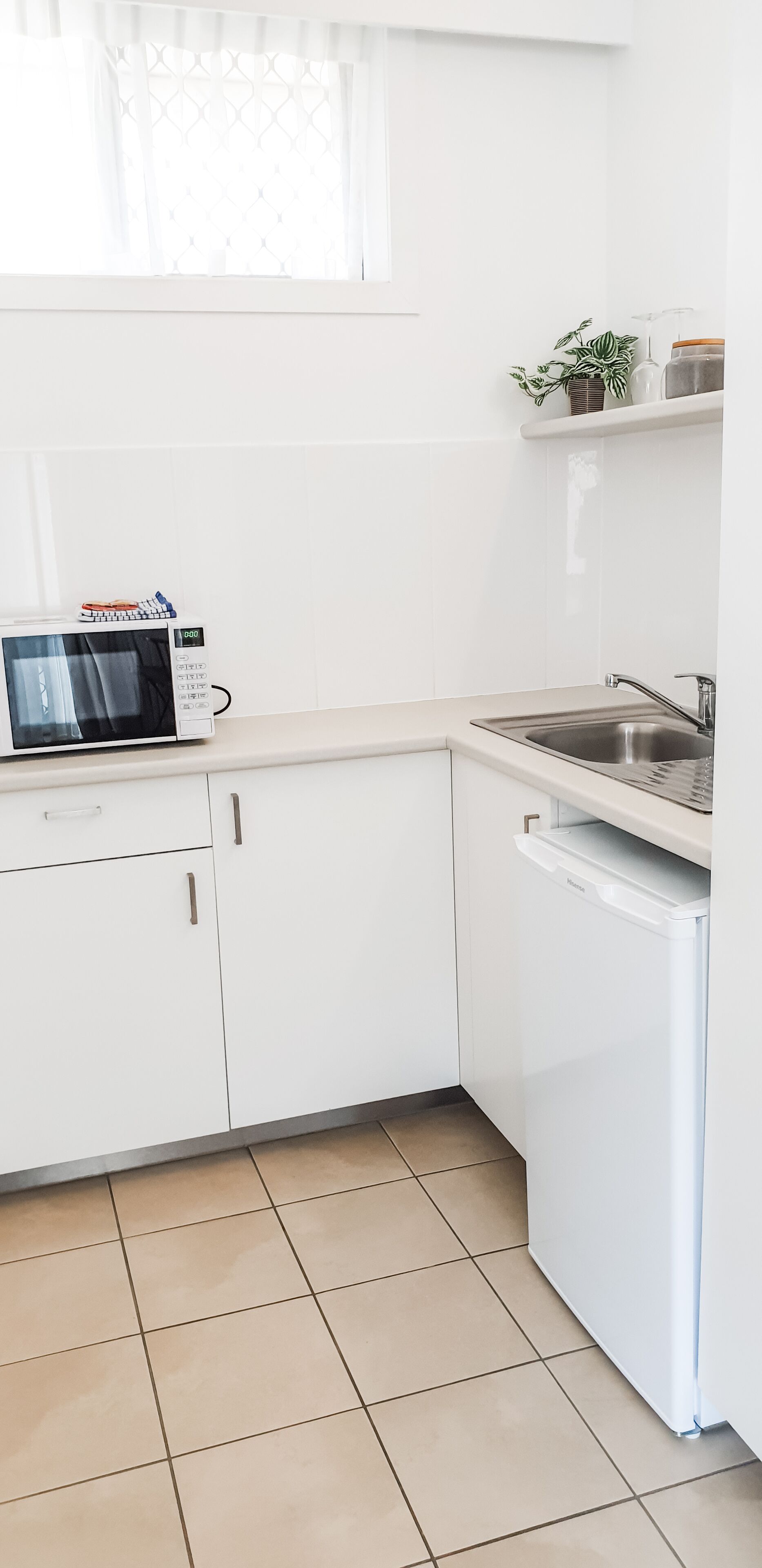 A kitchen with white cabinets, a microwave, a sink, and a dishwasher.
