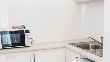 A kitchen with white cabinets, a microwave, a sink, and a dishwasher.