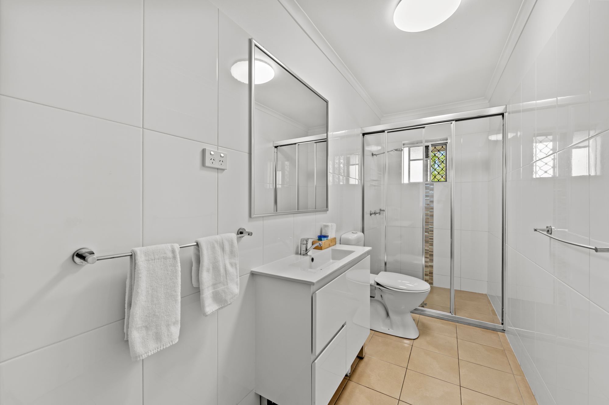 A modern bathroom with a glass shower enclosure, a white sink, and a toilet.