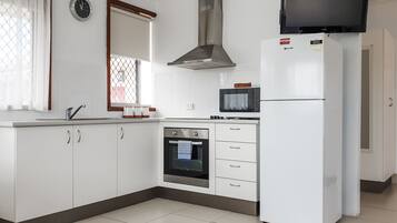 A modern kitchen with white cabinets, a built-in oven, a microwave, and a refrigerator.