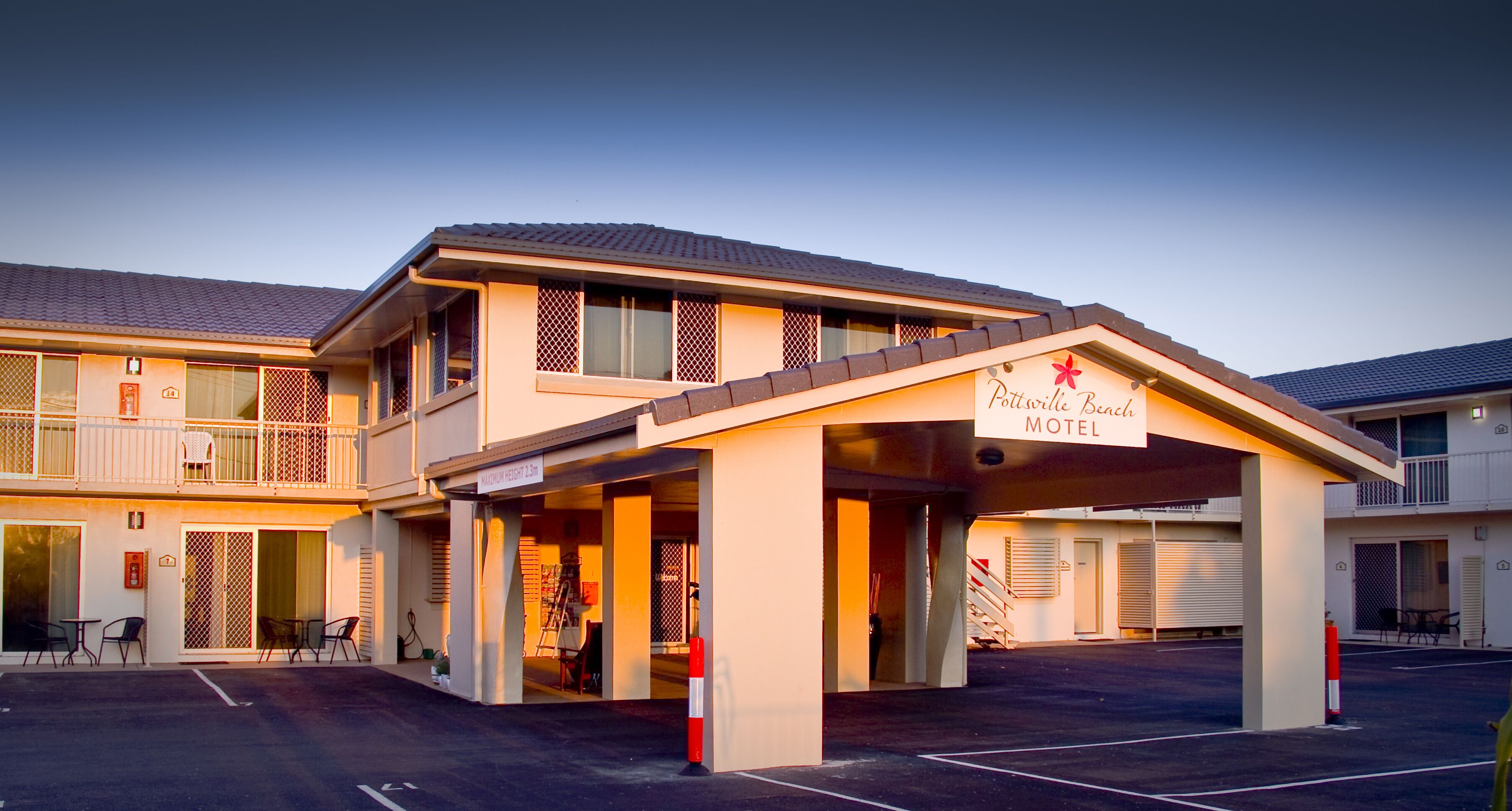 Um motel com entrada coberta, área de estar ao ar livre e uma placa indicando o nome.