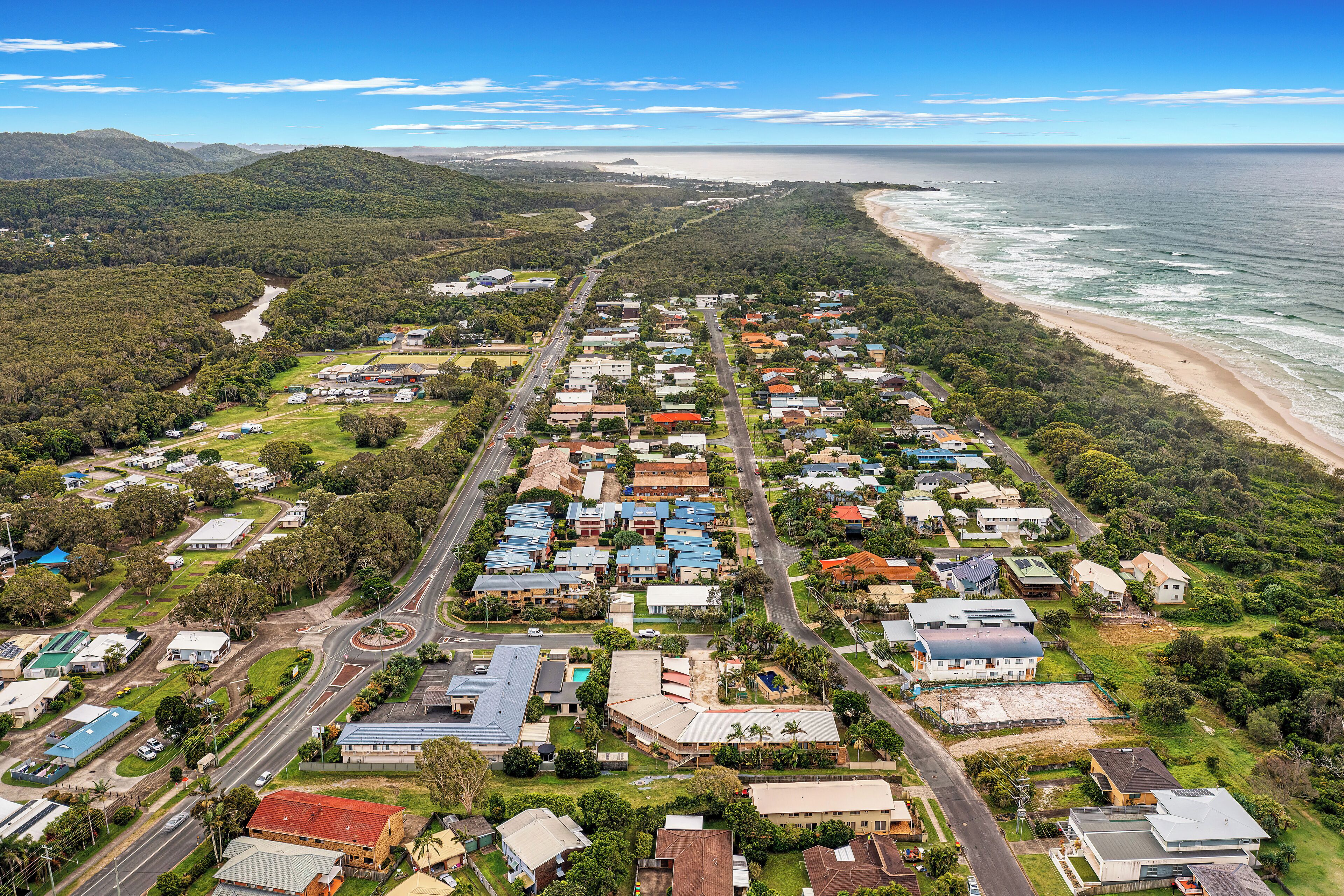 An aerial view of a coastal residential area with houses, roads, and a beach.
