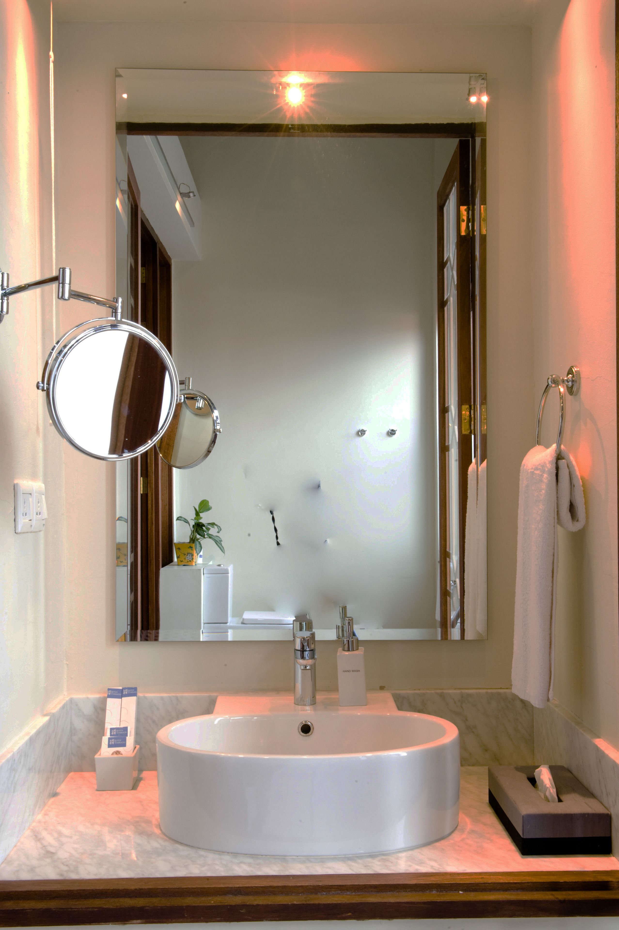 A bathroom with a round sink, a mirror, and a towel rack.