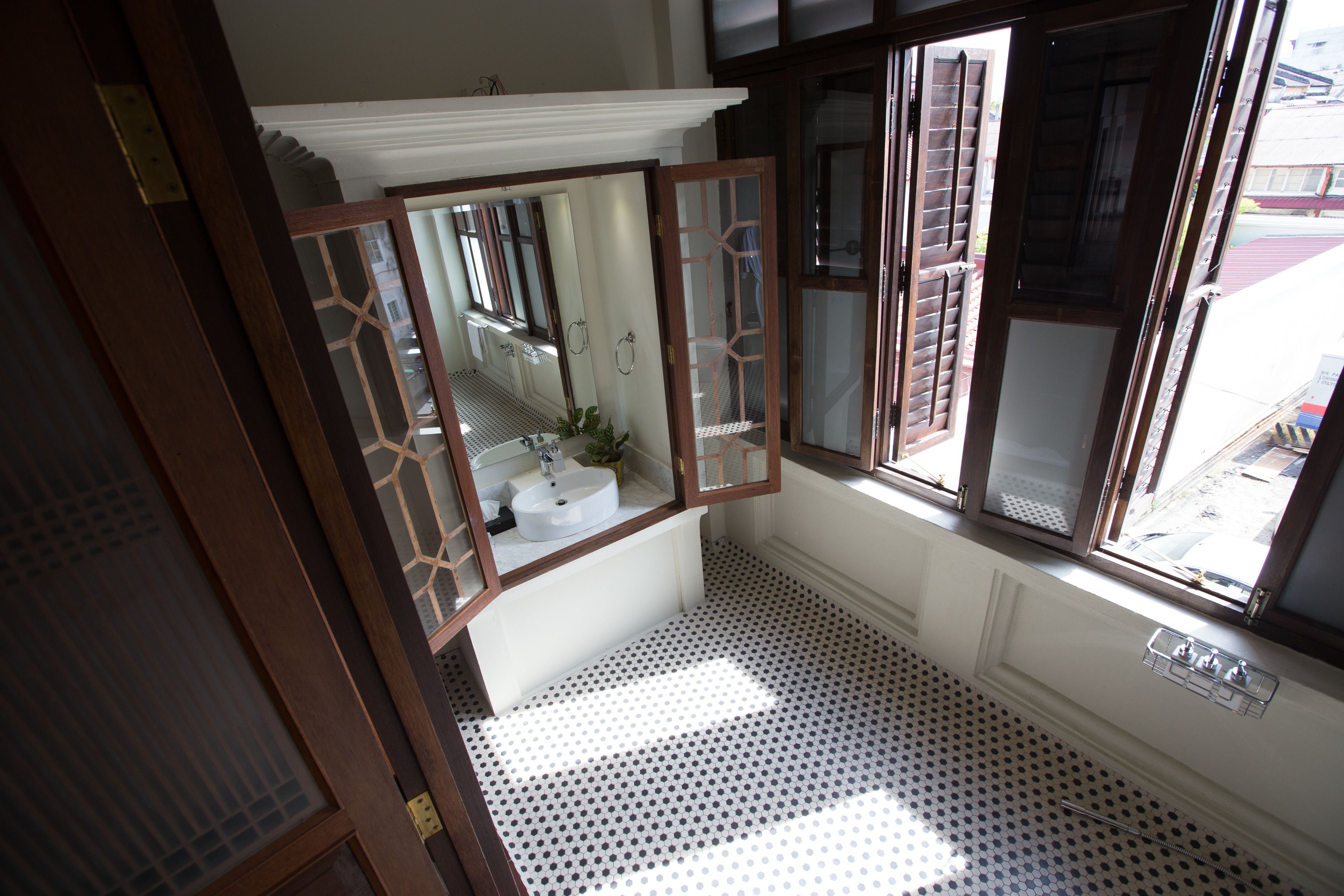 A bathroom with a white sink, a mirror, and a patterned floor.