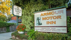 A sign for The Armour Motor Inn with amenities like a swimming pool, sauna, wireless internet, queen size beds, family units, and guide dogs excepted.
