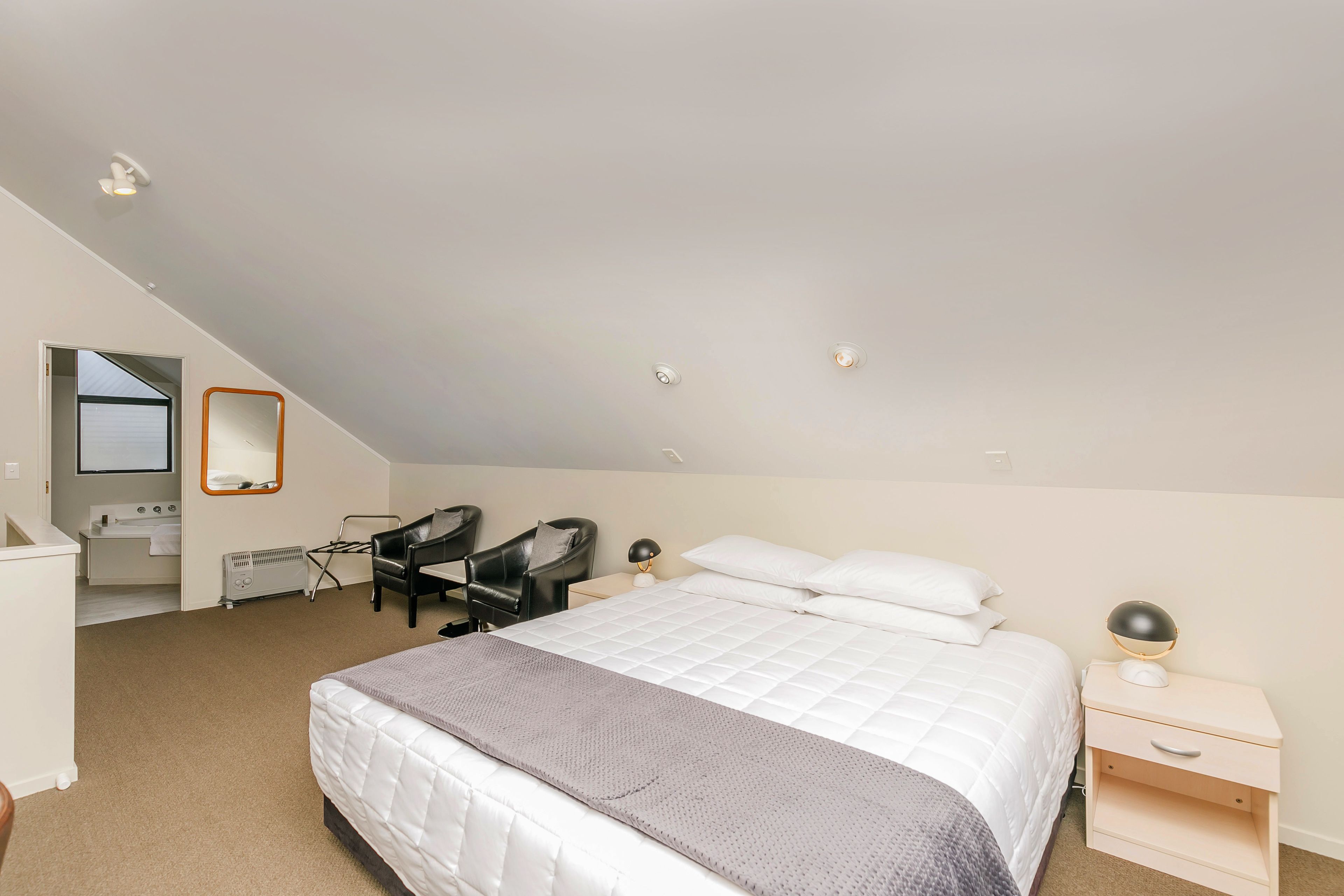 Une chambre à coucher comprenant un lit, une table de chevet, une chaise et un bureau avec une autre chaise.