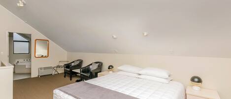 Une chambre à coucher comprenant un lit, une table de chevet, une chaise et un bureau avec une autre chaise.
