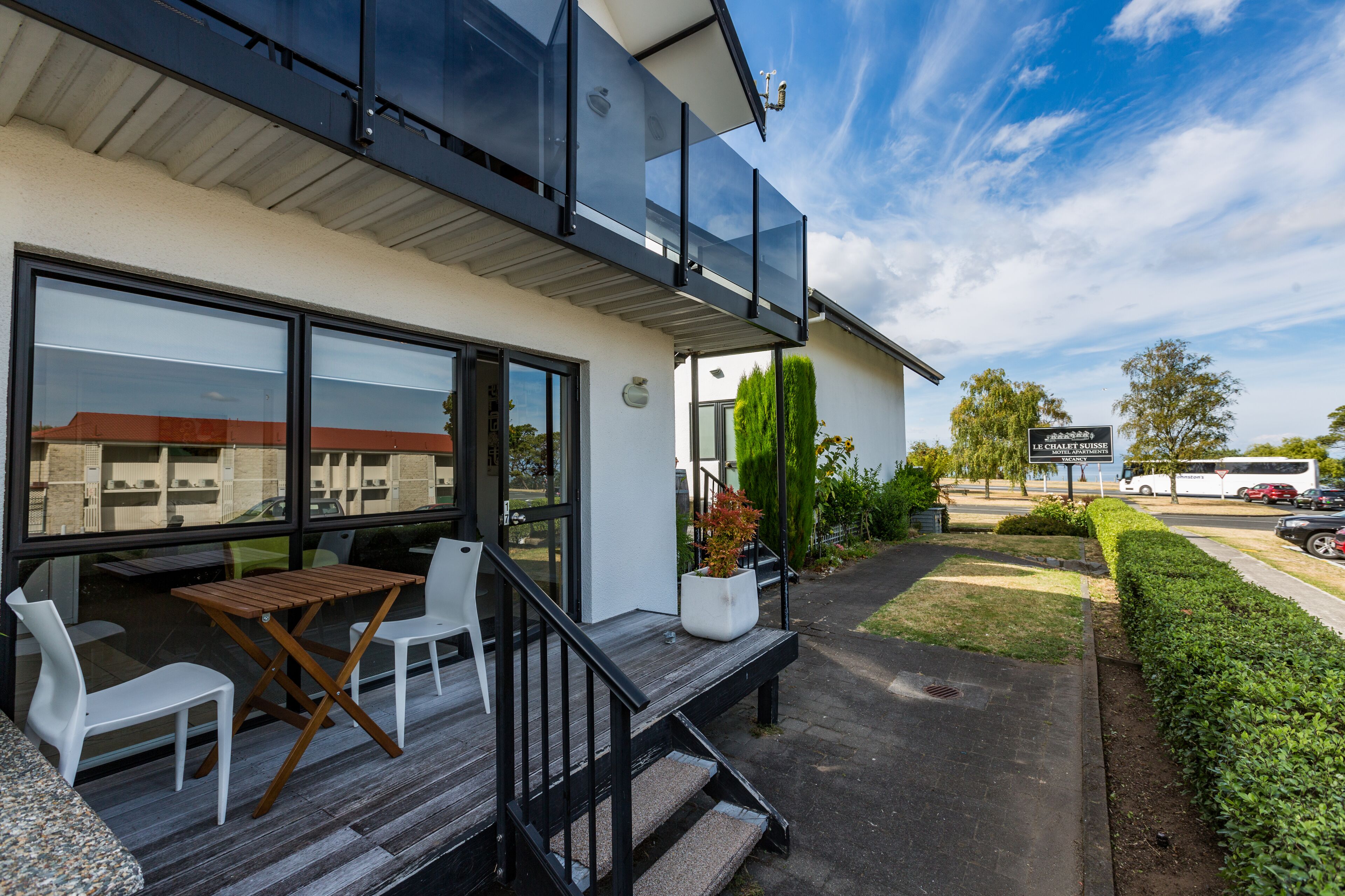 Een modern gebouw met een balkon, terras en een bord waarop hotel staat.