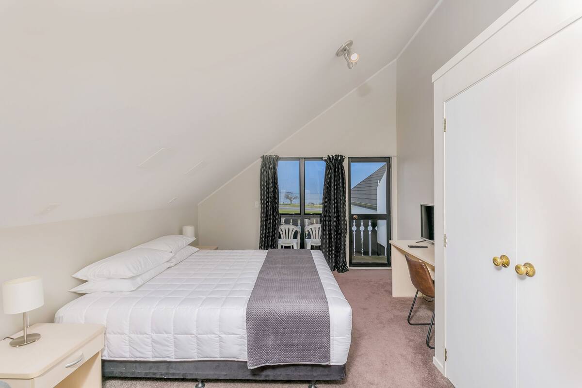 Une chambre à coucher comprenant un lit, une table de chevet et un bureau avec une chaise.